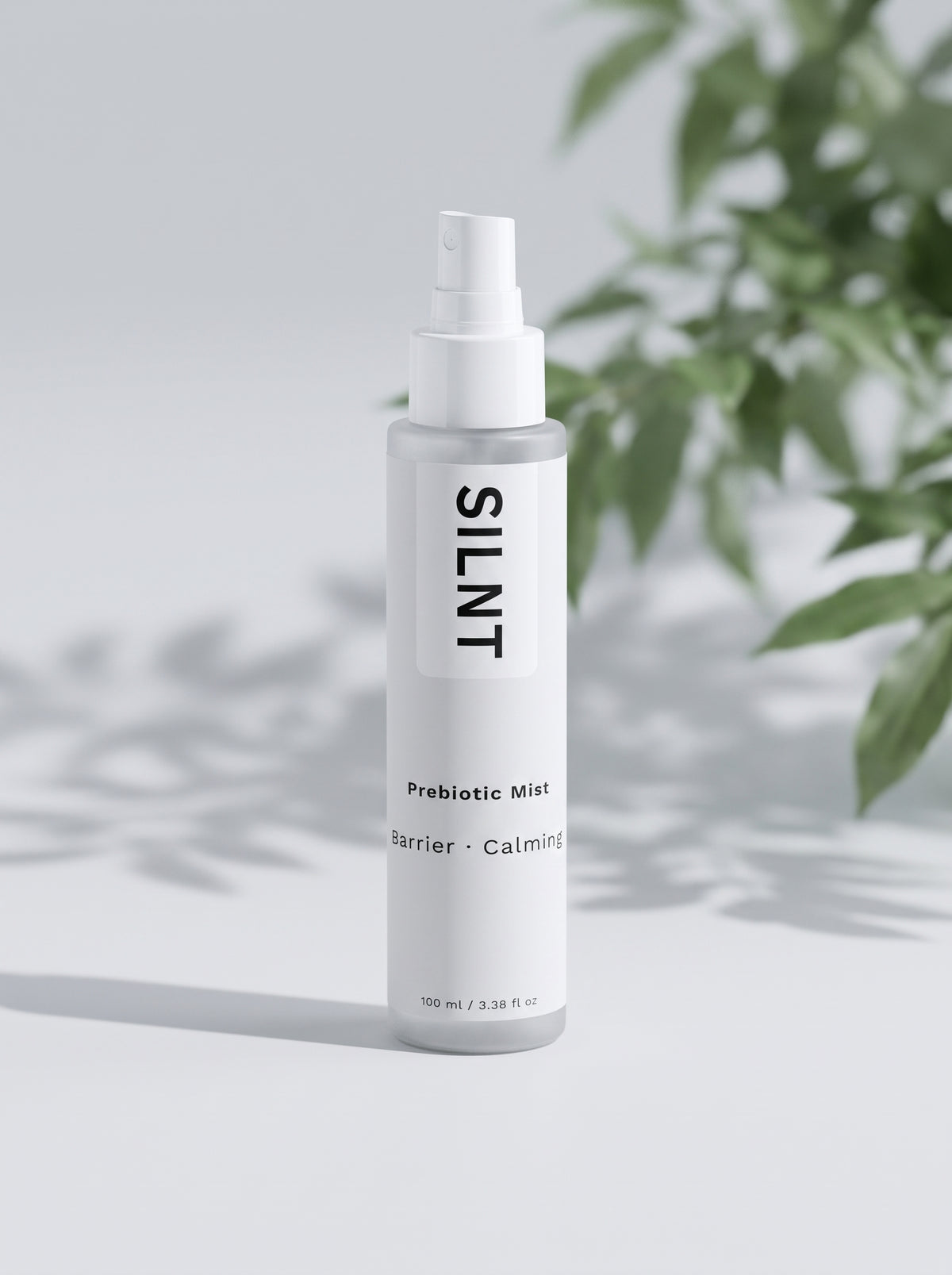 SILNT Prebiotic Mist bottle beside a leafy plant casting soft shadows