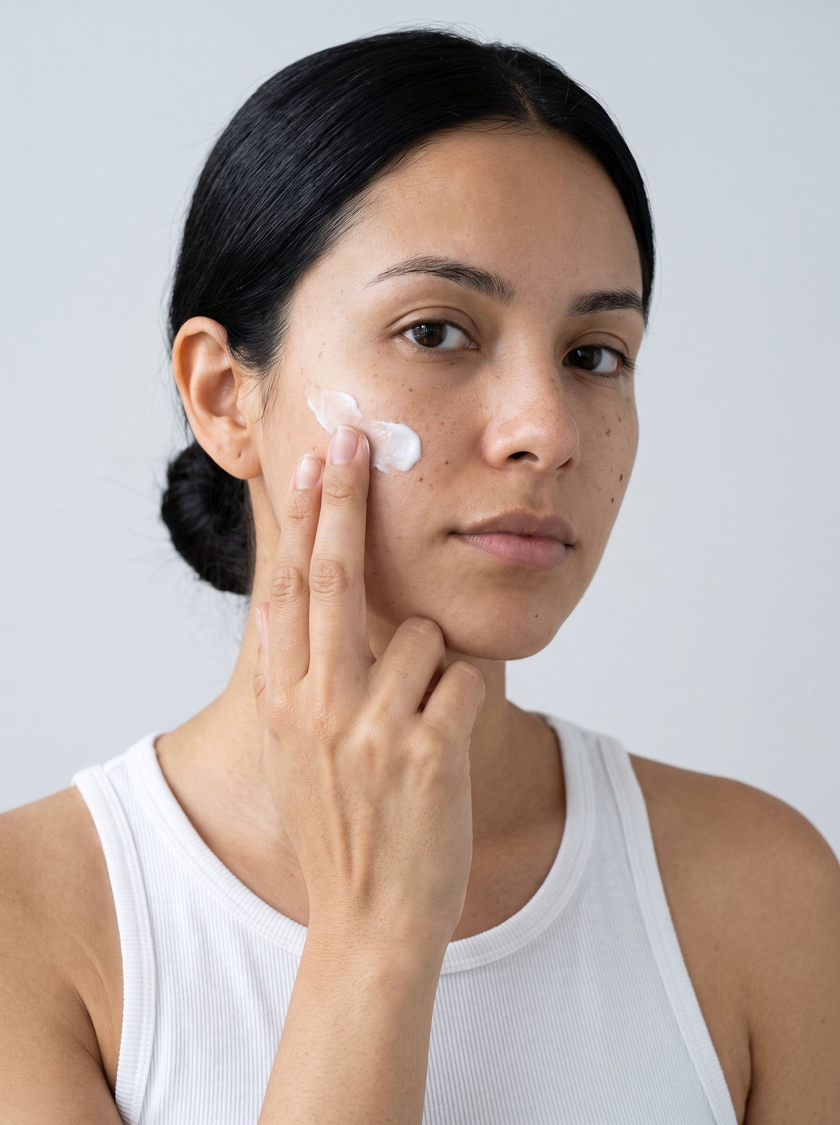 SILNT Overnight Cream smoothed along a model's cheekbone, white tank top, light grey background