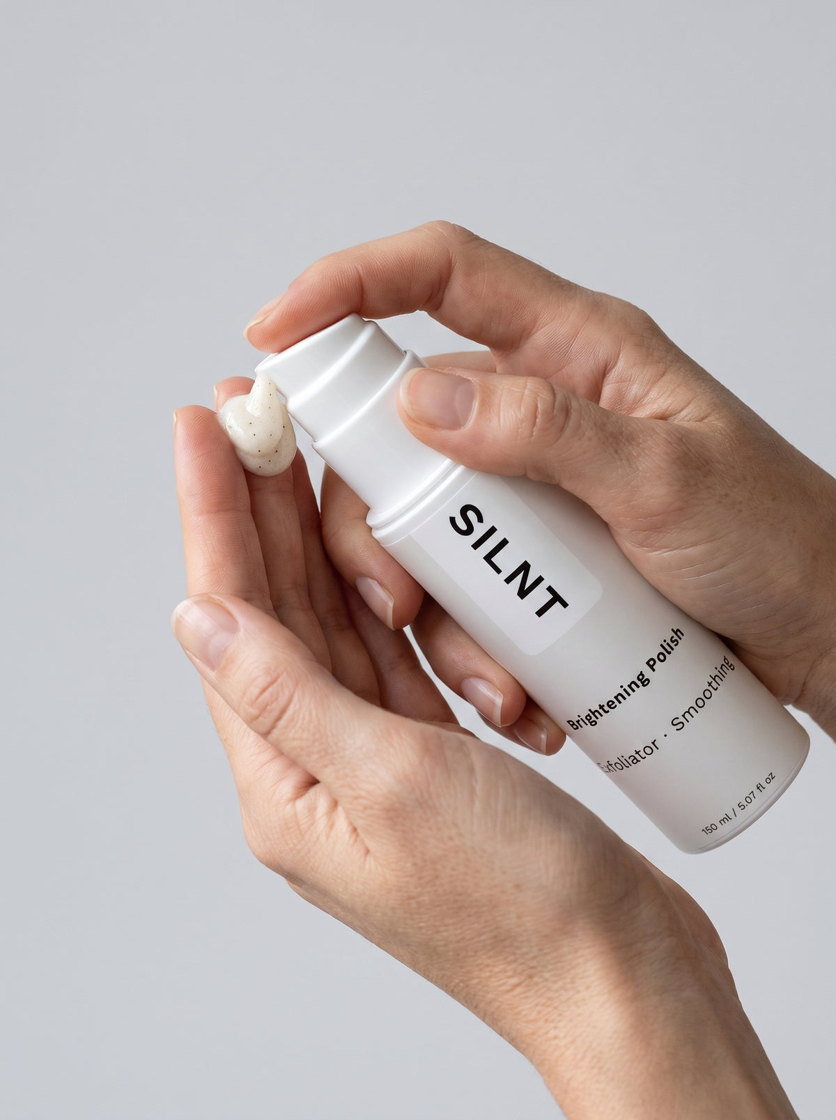 Hands holding the SILNT Brightening Polish pump bottle