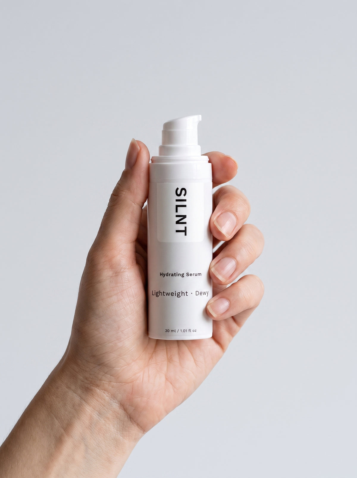 SILNT Hydrating Serum bottle held upright in one hand against a light grey background