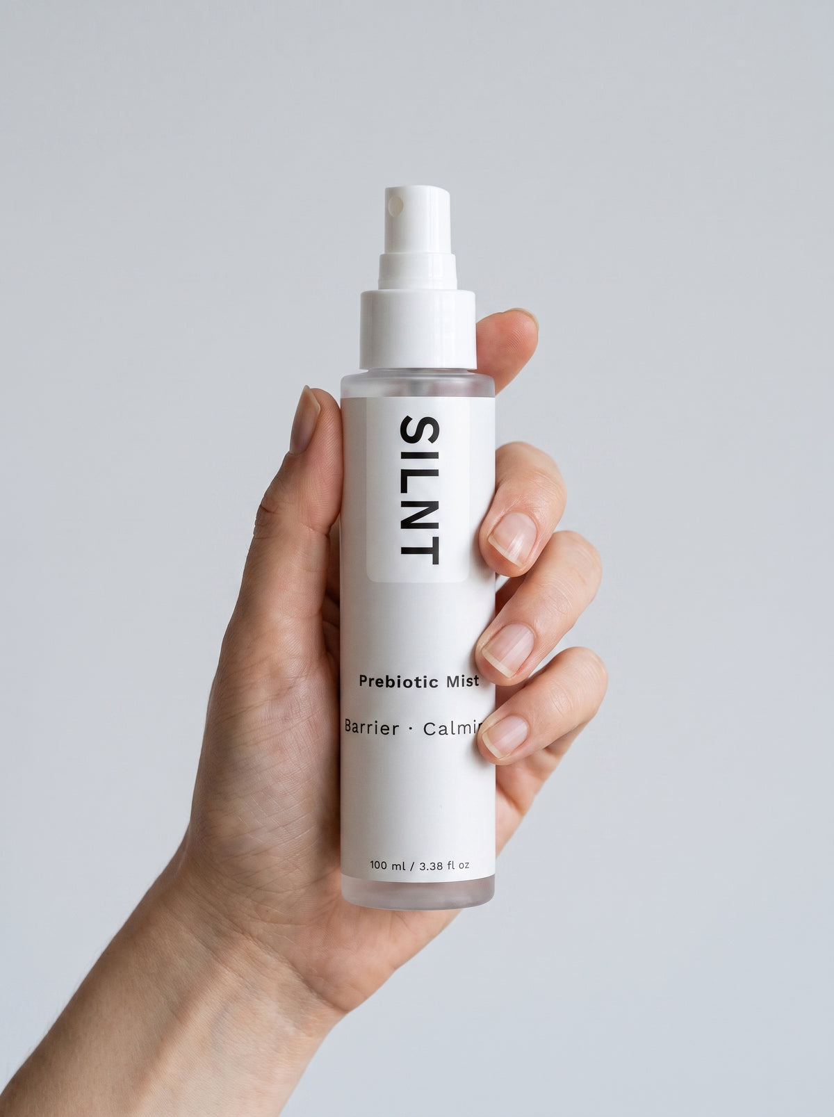 Hand holding the SILNT Prebiotic Mist spray bottle upright
