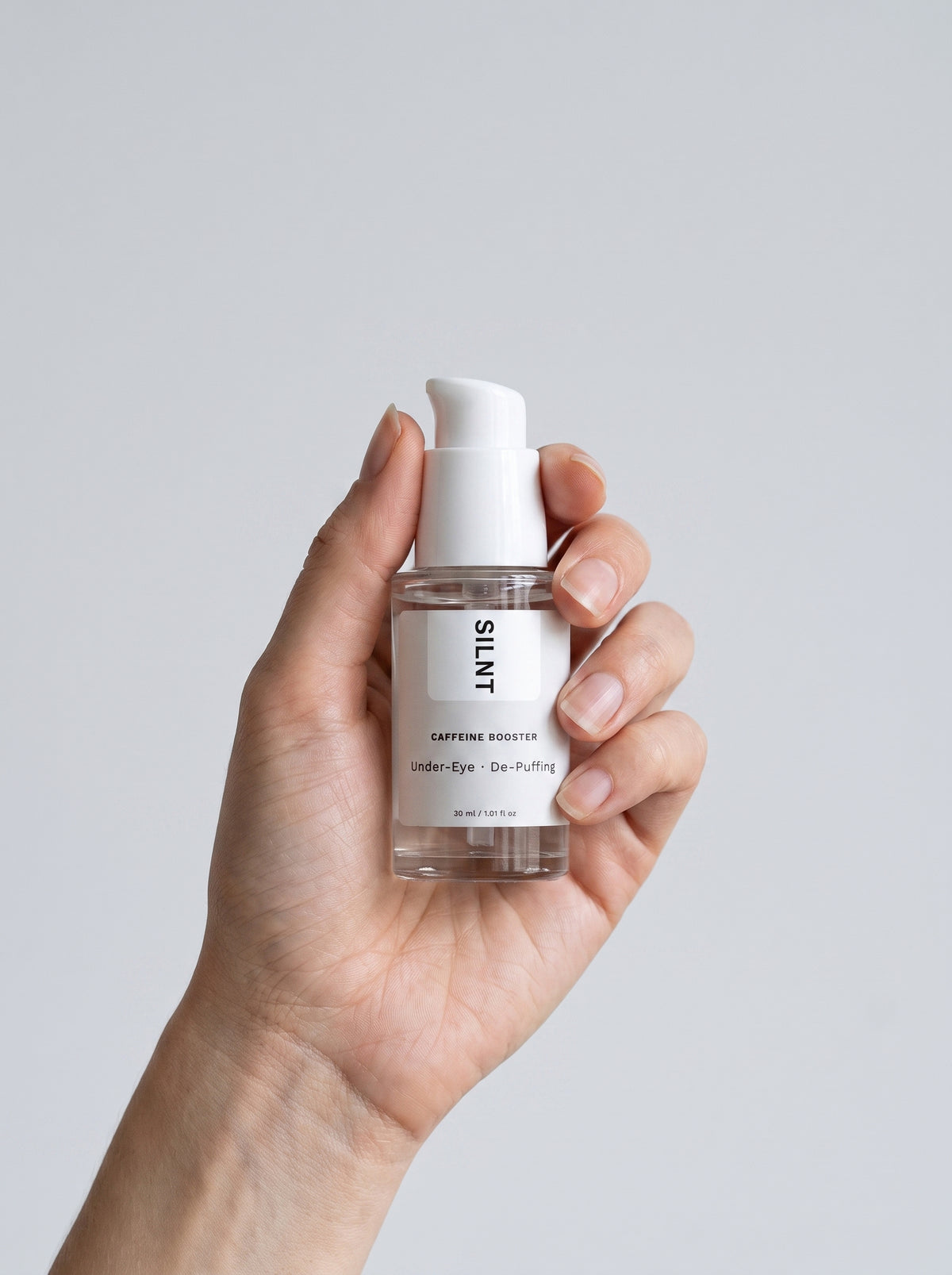 Hand holding the SILNT Caffeine Booster pump bottle upright