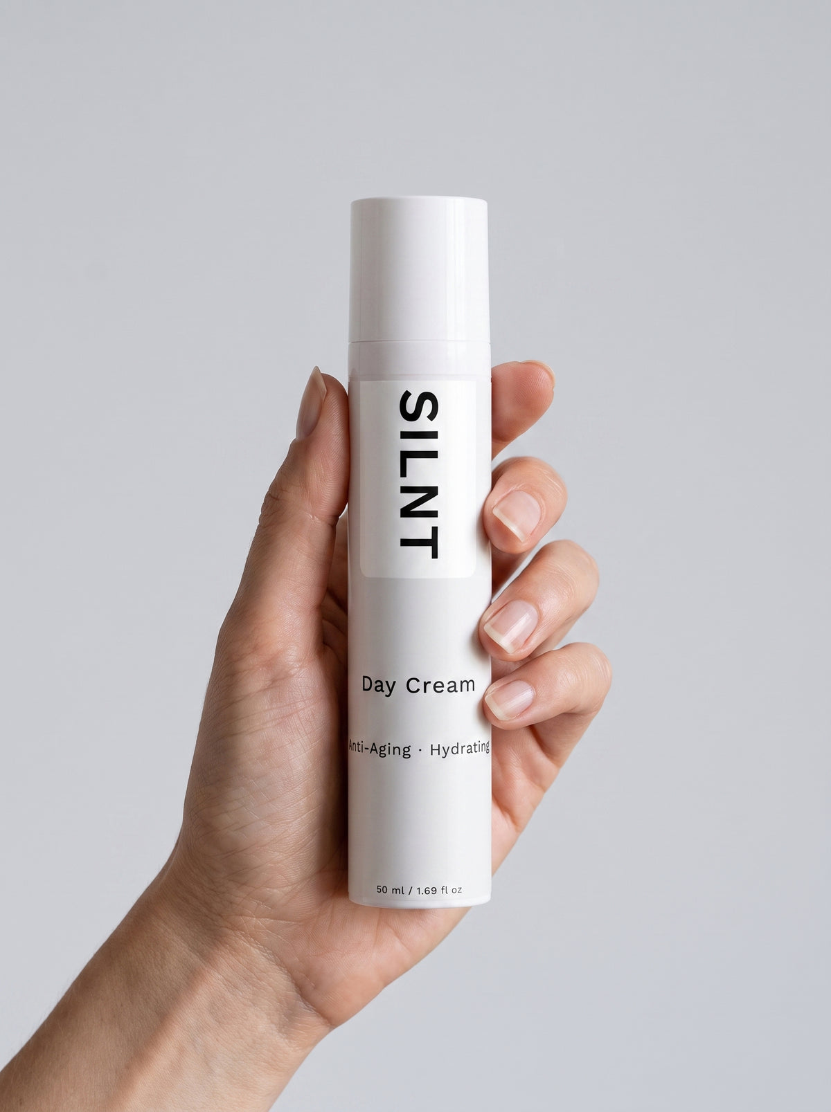SILNT Day Cream bottle held upright in one hand against a light grey background
