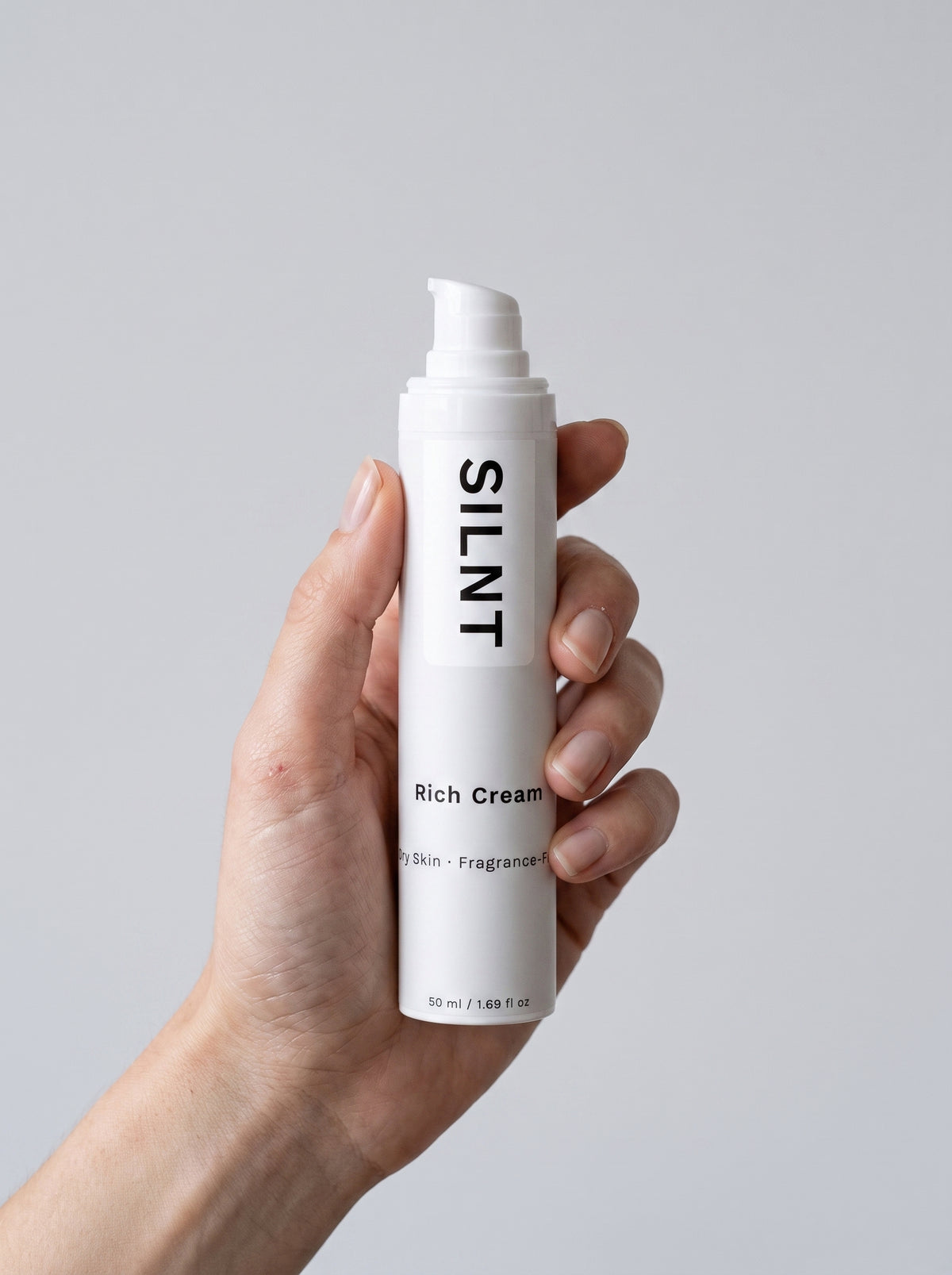 SILNT Rich Cream bottle held upright in one hand against a light grey background