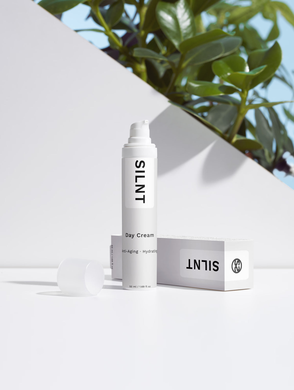SILNT Day Cream bottle beside its carton with soft leaf shadows on a light grey background