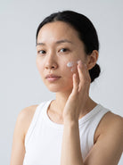 SILNT Overnight Cream applied to a model's cheek with her fingertips, white tank top, light grey background