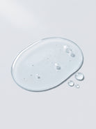Clear liquid toner droplet of SILNT Glycolic Toner showing its transparent texture and small bubbles