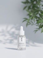 SILNT Prebiotic Serum bottle beside a leafy plant casting soft shadows