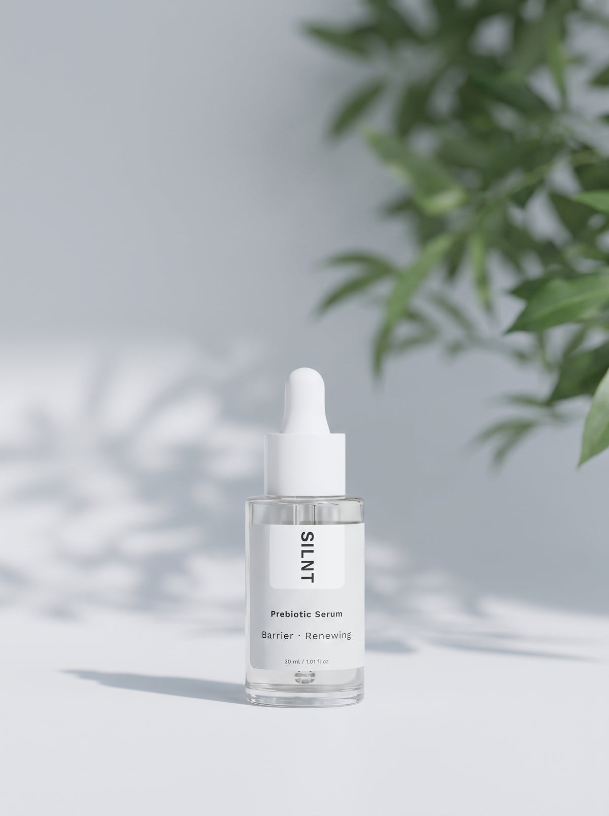 SILNT Prebiotic Serum bottle beside a leafy plant casting soft shadows