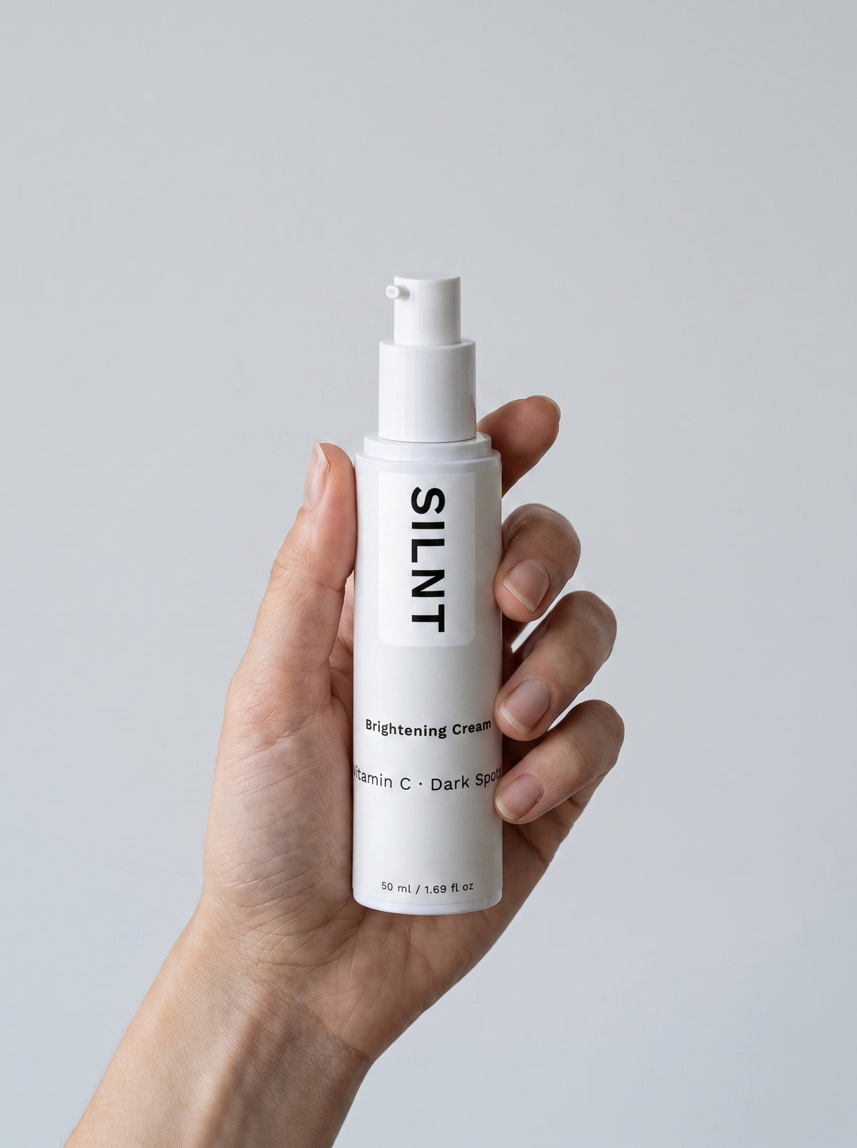 Hand holding the SILNT Brightening Cream bottle at an angle