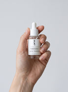 Hand holding the SILNT Prebiotic Serum dropper bottle