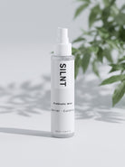 SILNT Prebiotic Mist bottle beside a leafy plant casting soft shadows