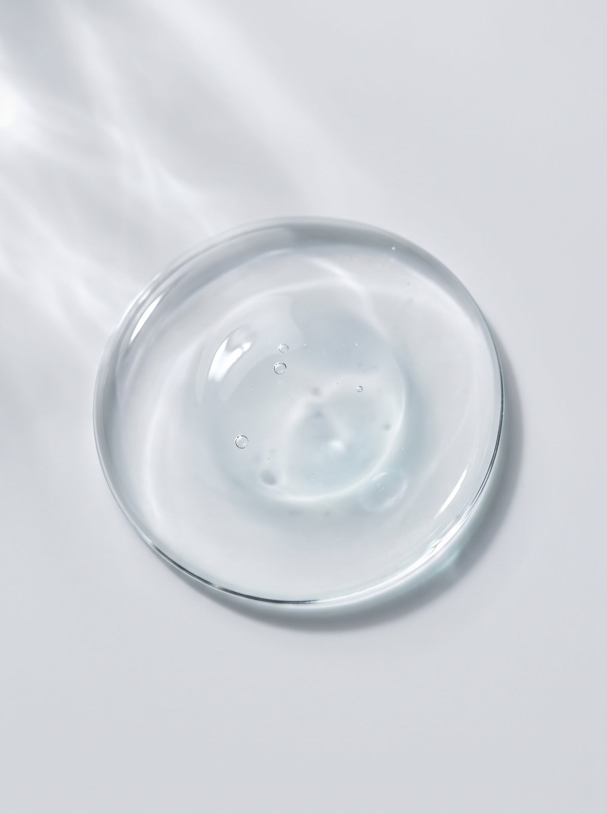 SILNT Exfoliating Concentrate clear gel swatch in a glass dish on a light grey background