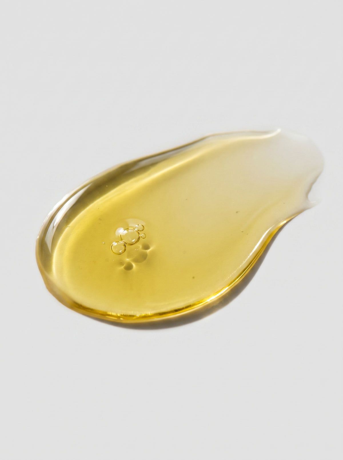 SILNT Bakuchiol Serum golden oil swatch with a glossy finish on a light grey background