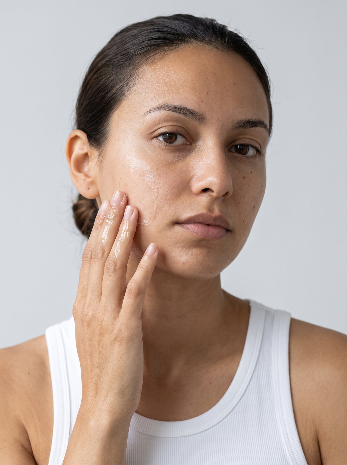 SILNT Hydration Gel smoothed along a model's cheekbone, white tank top, light grey background