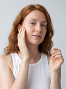 Red-haired woman smoothing SILNT Brightening Cream onto her face