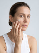 SILNT Day Cream smoothed along a model's cheekbone, white tank top, light grey background