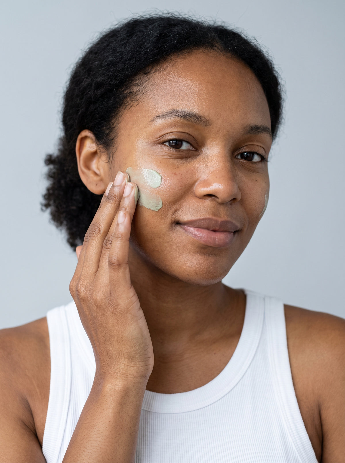 SILNT Clarifying Moisturiser smoothed along a model's cheekbone, white tank top, light grey background