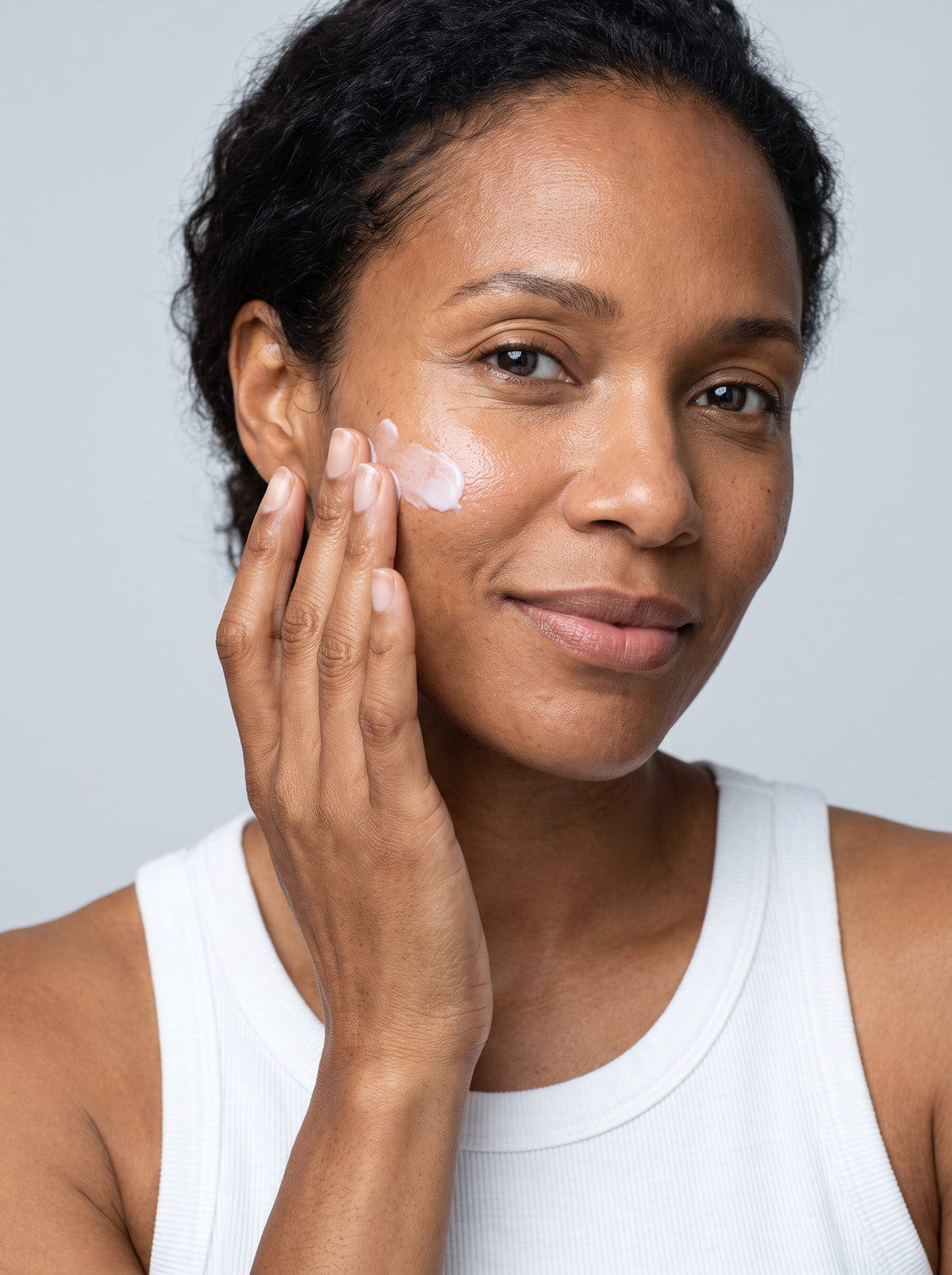 SILNT Retinol Alternative Cream smoothed along a model's cheekbone, white tank top, light grey background