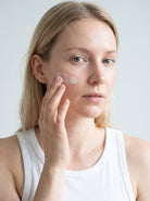 SILNT Rich Cream smoothed along a model's cheekbone, white tank top, light grey background