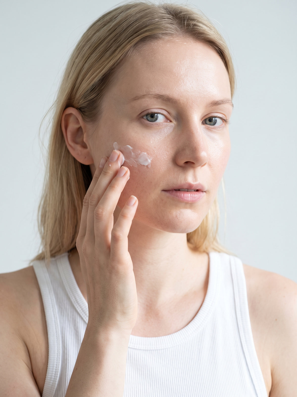 SILNT Rich Cream smoothed along a model's cheekbone, white tank top, light grey background