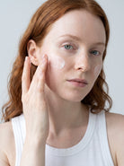 SILNT Rich Cream applied to a model's cheek with her fingertips, white tank top, light grey background
