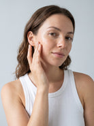 SILNT Bakuchiol Serum smoothed along a model's cheekbone, white tank top, light grey background