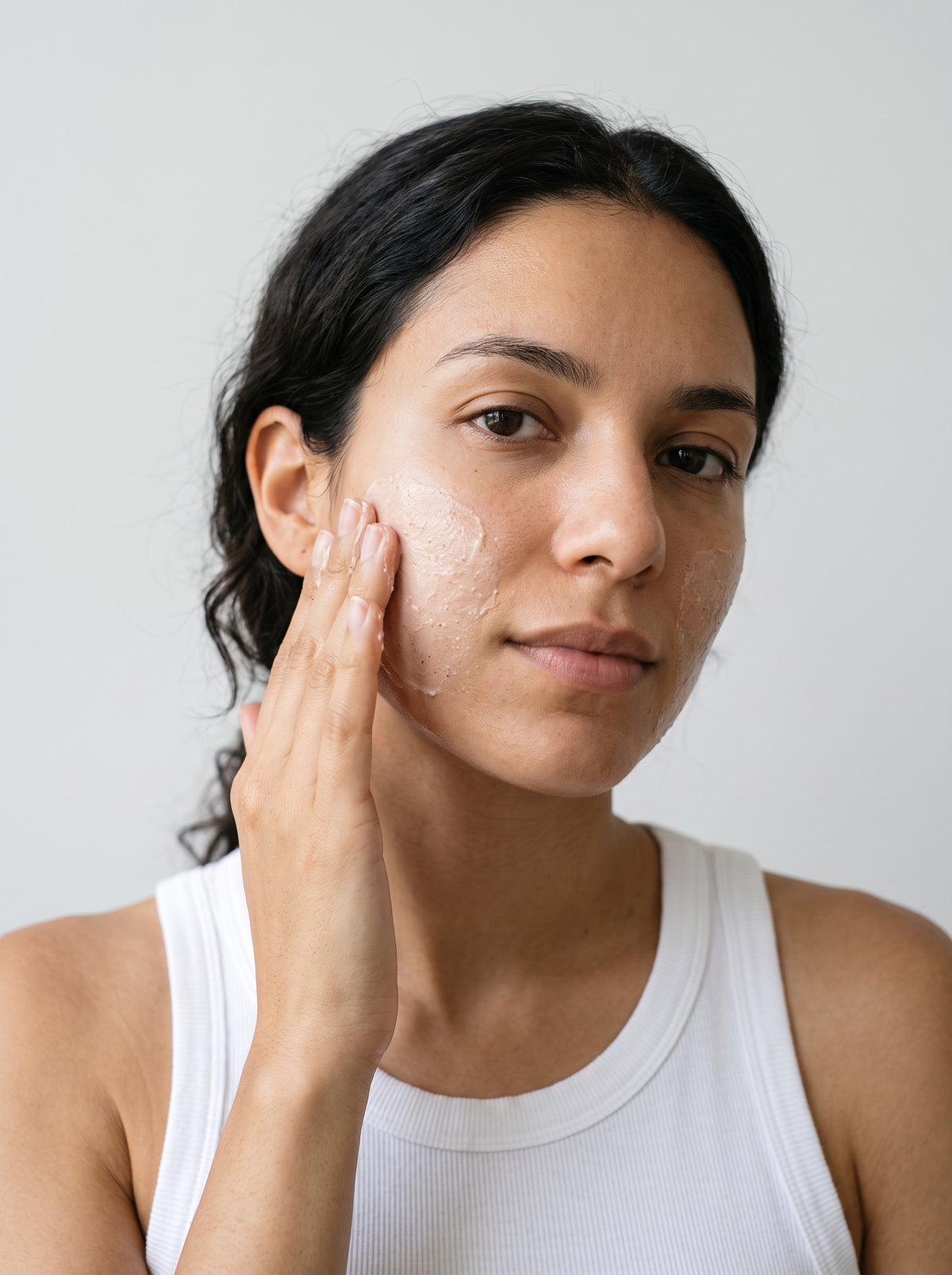Close-up of a woman smoothing SILNT Brightening Polish onto her cheek