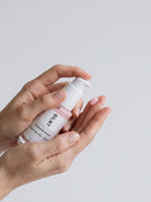 Hands holding the SILNT Exosome Serum pump bottle