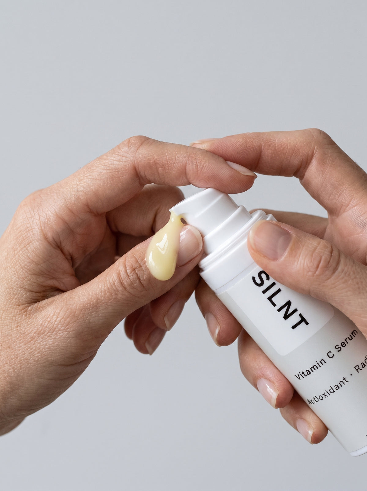 Hand dispensing SILNT Vitamin C Serum from the pump bottle