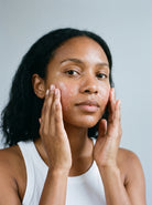 SILNT Radiance Cleanser massaged over a model's cheeks with both hands, white tank top, light grey background