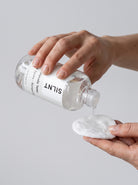 Hand pouring SILNT Glycolic Toner from the bottle onto a cotton pad