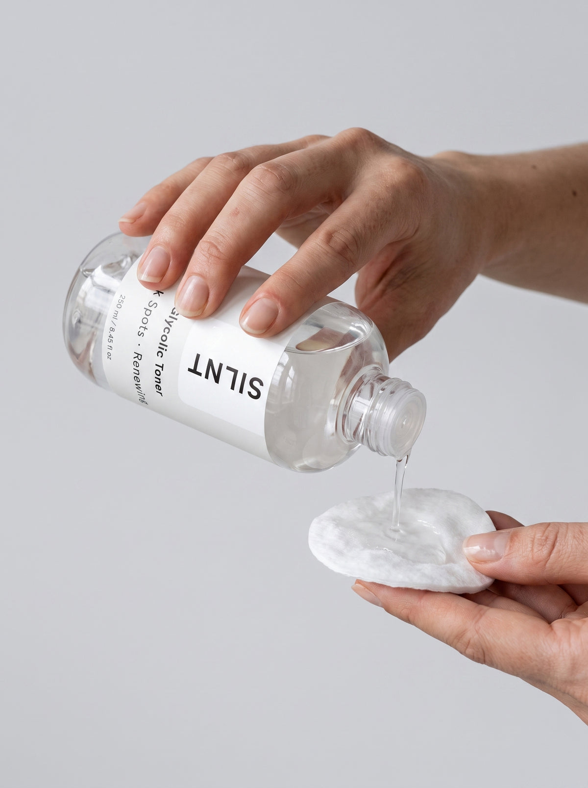 Hand pouring SILNT Glycolic Toner from the bottle onto a cotton pad