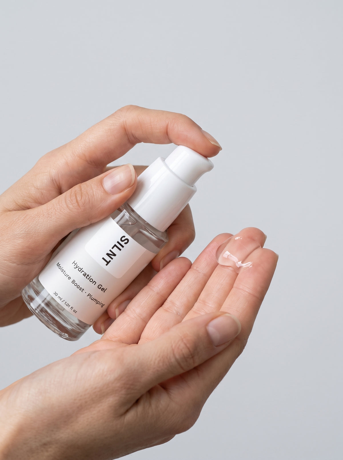 SILNT Hydration Gel bottle held in both hands with the pump facing forward, light grey background