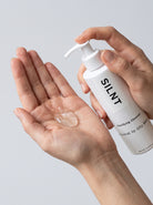 SILNT Clarifying Cleanser clear gel dispensed into an open palm from the pump bottle, light grey background