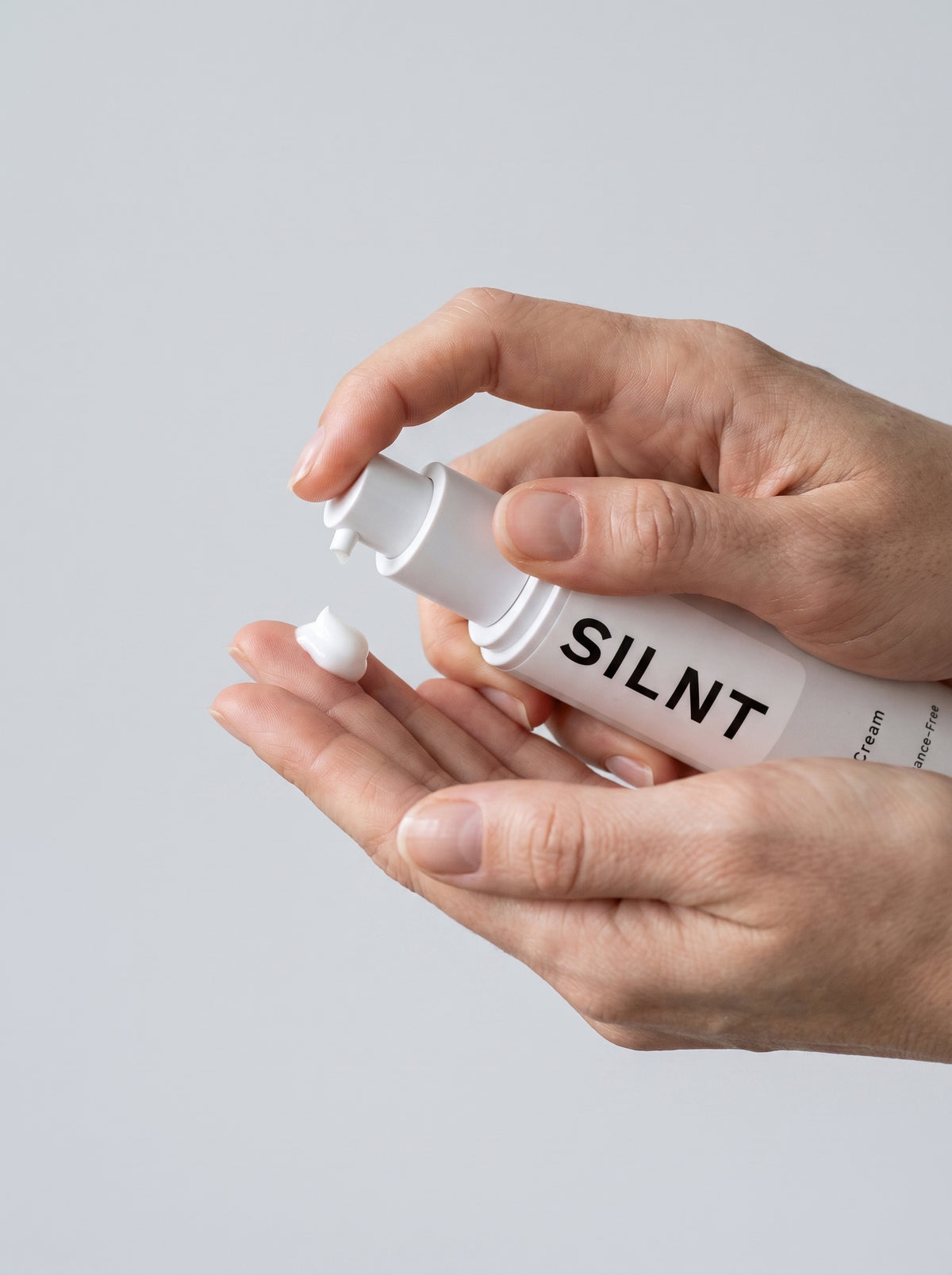 SILNT Overnight Cream bottle held in both hands with the pump facing forward, light grey background