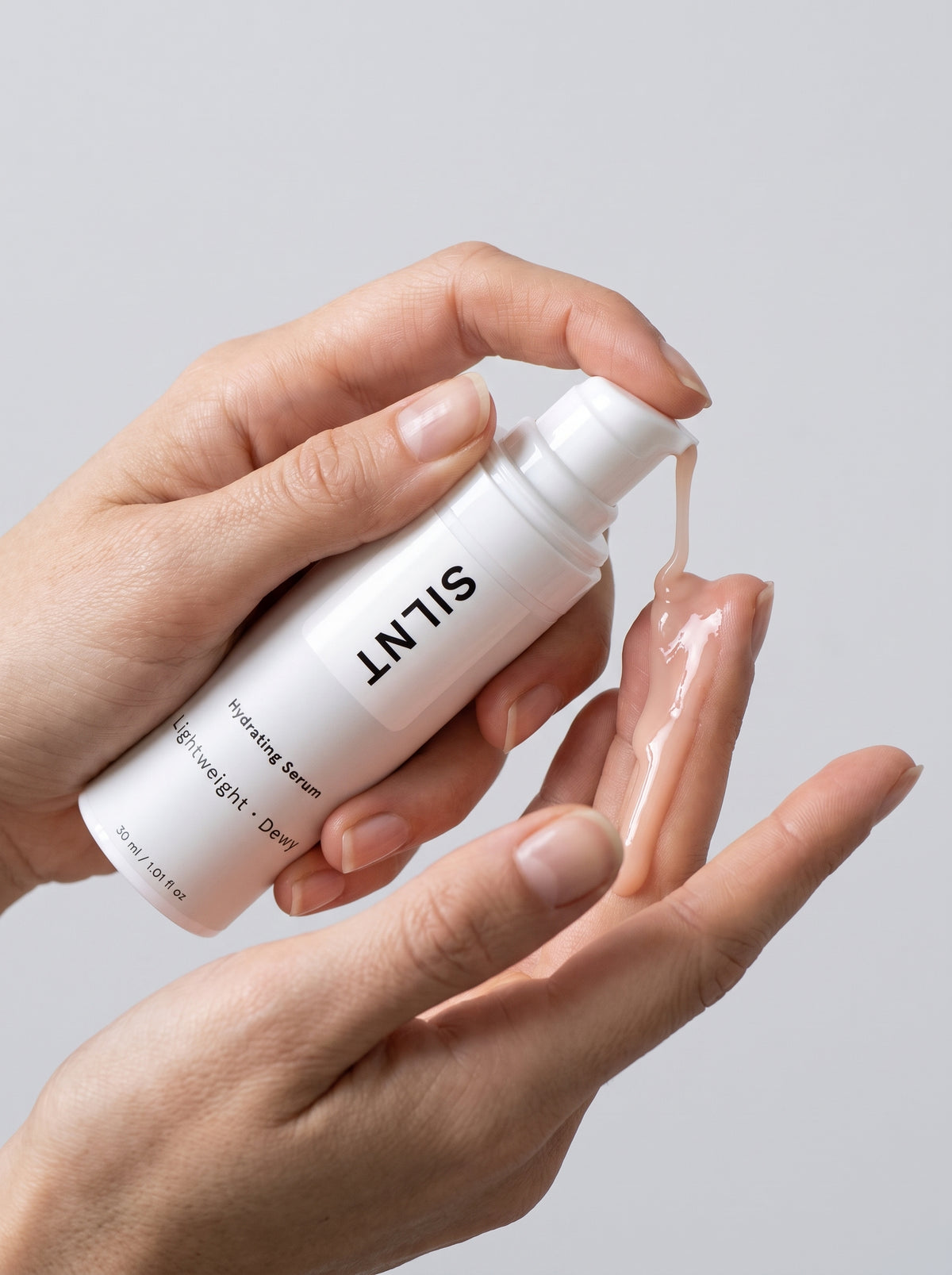 SILNT Hydrating Serum bottle held in both hands with the pump facing forward, light grey background