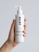SILNT Clarifying Cleanser bottle held upright in one hand, showing its 200 ml size, light grey background