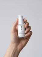 SILNT Plumping Serum bottle held upright in one hand against a light grey background