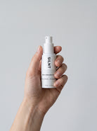 SILNT Retinol Alternative Cream bottle held upright in one hand against a light grey background