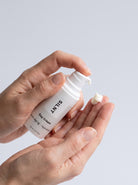 SILNT Day Cream travel size bottle held in both hands with the pump facing forward, light grey background