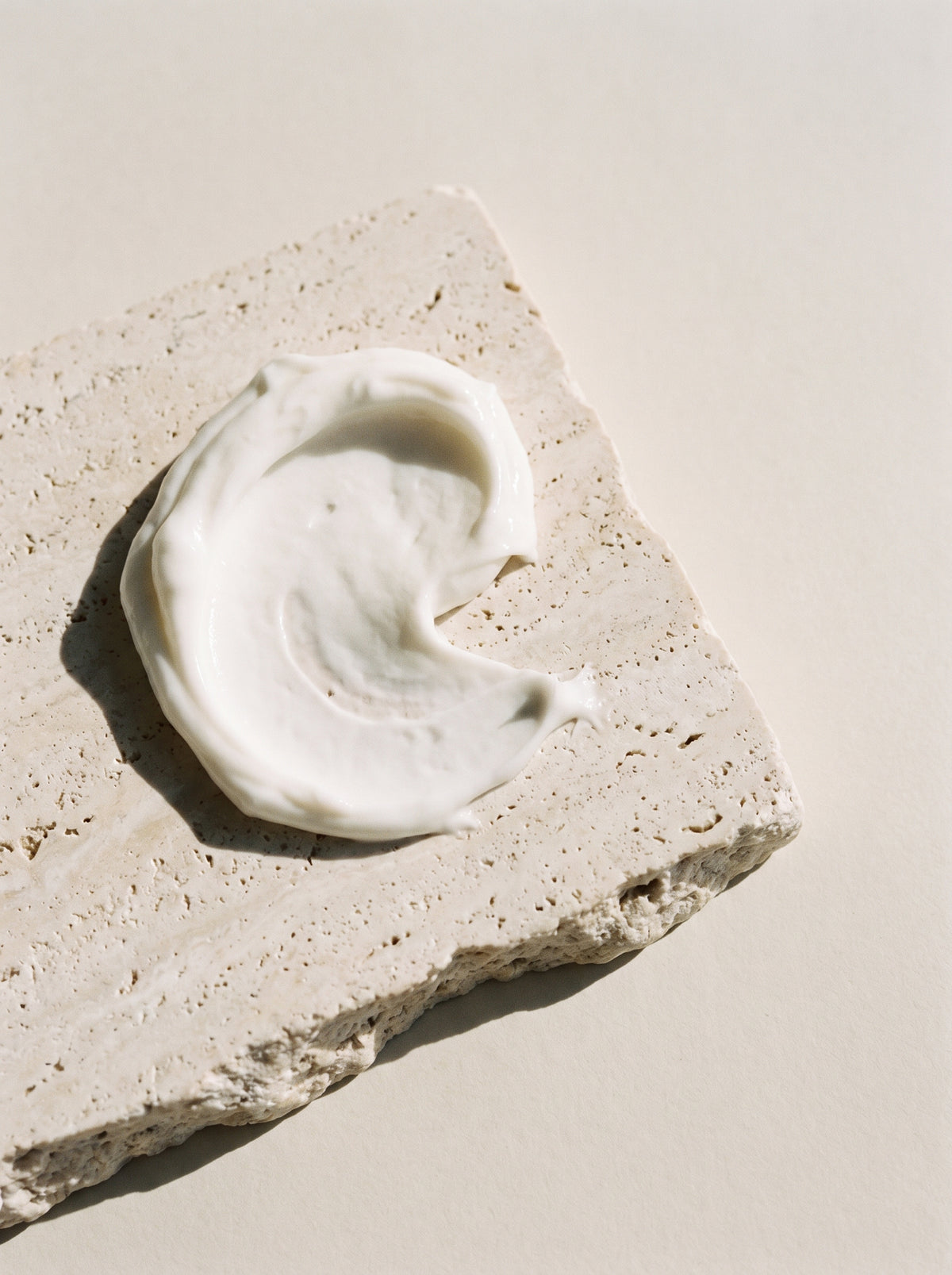 A swirl of white cream on a slab of travertine in soft sunlight