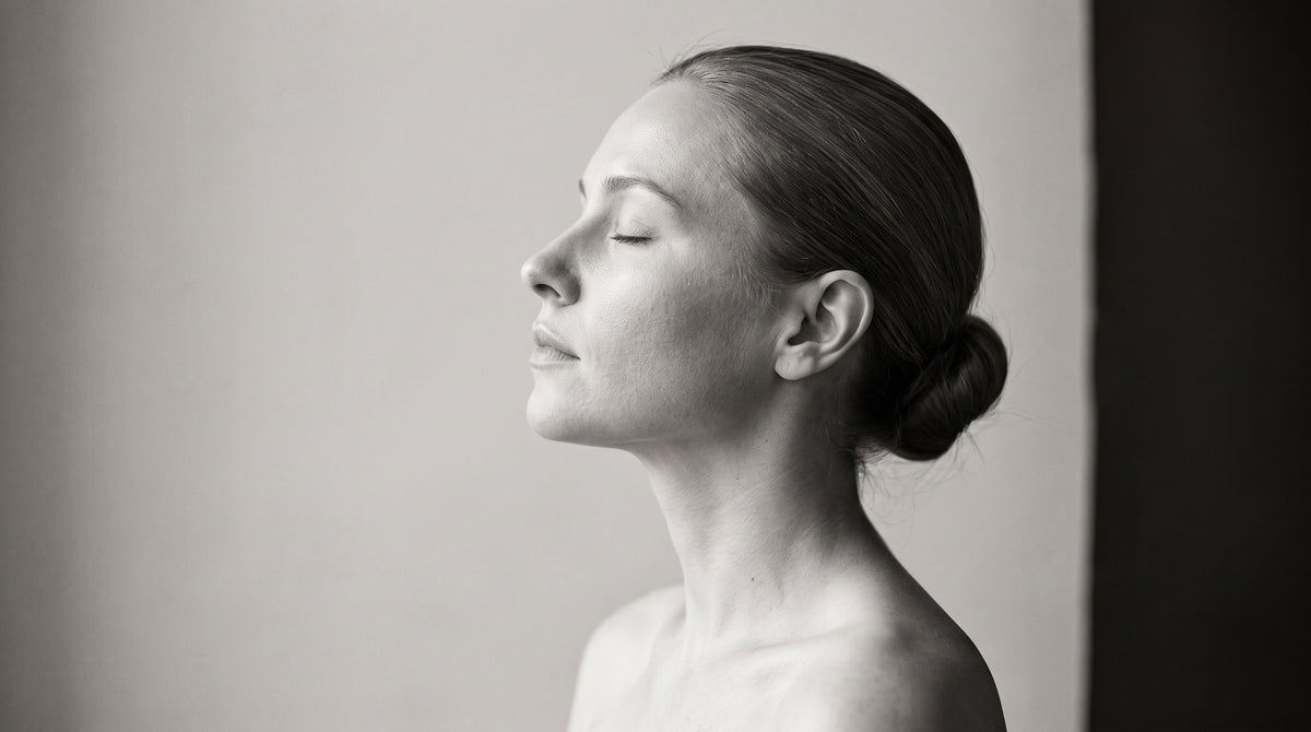 A woman in profile with her eyes closed, in soft window light