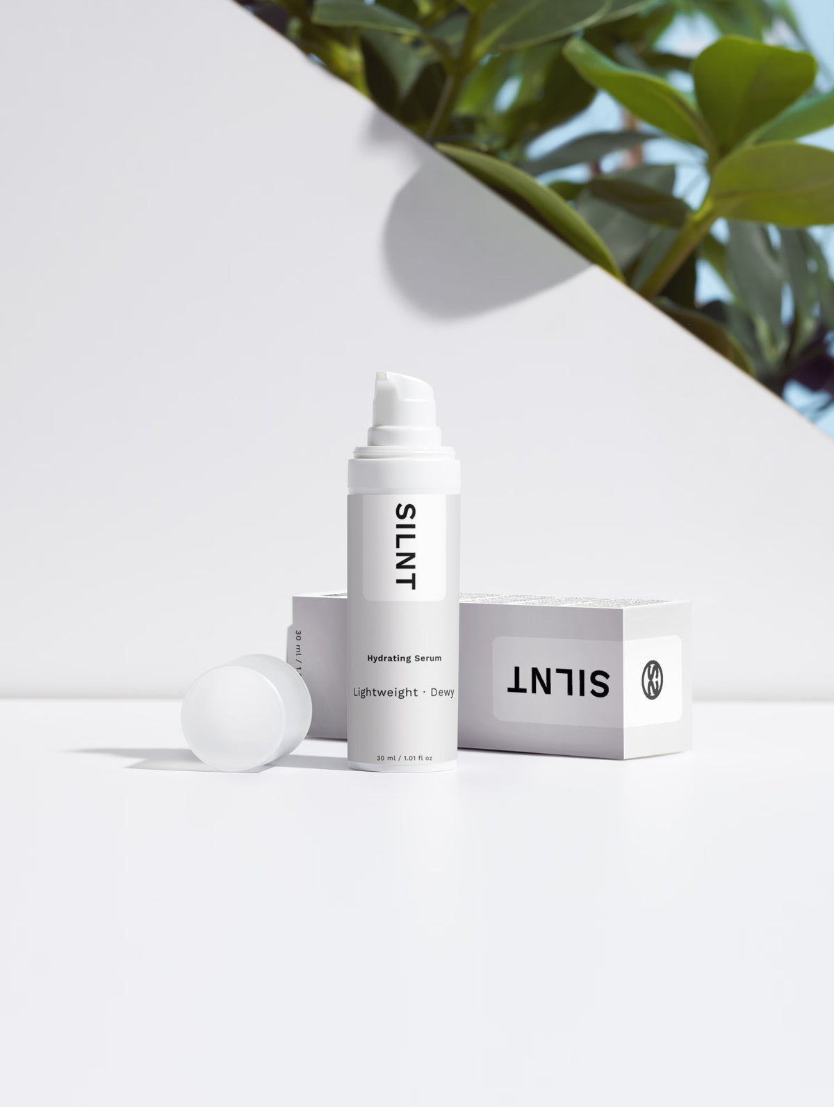 SILNT Hydrating Serum bottle beside its carton with soft leaf shadows on a light grey background